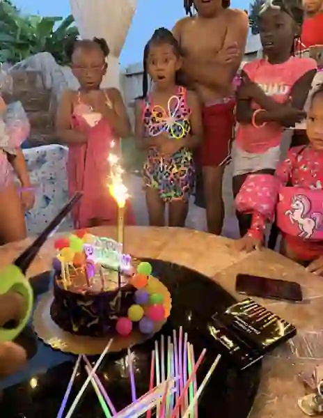 Children gathered around a birthday cake with a sparkler at Cypress River Oasis